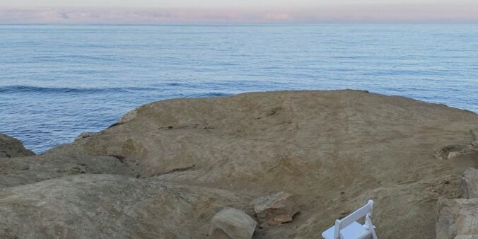 a couple of white chairs sitting on top of a rocky beach