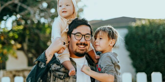 man in white shirt carrying girl in gray shirt